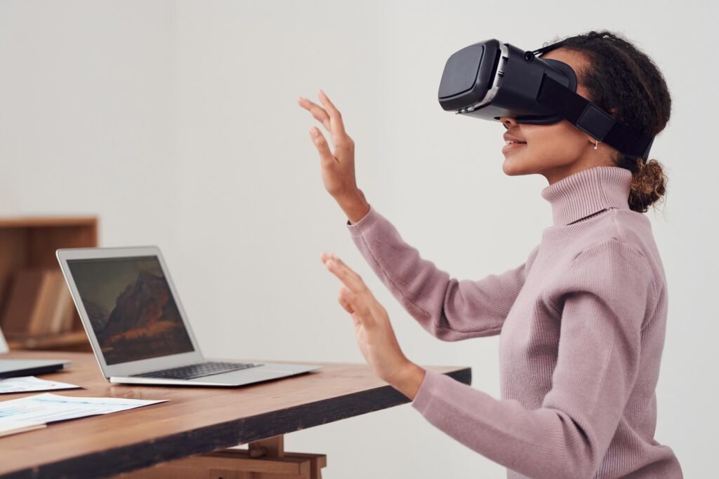 alt="a young female wearing a virtual display headset in front of an open laptop, a representation of education galaxy"
