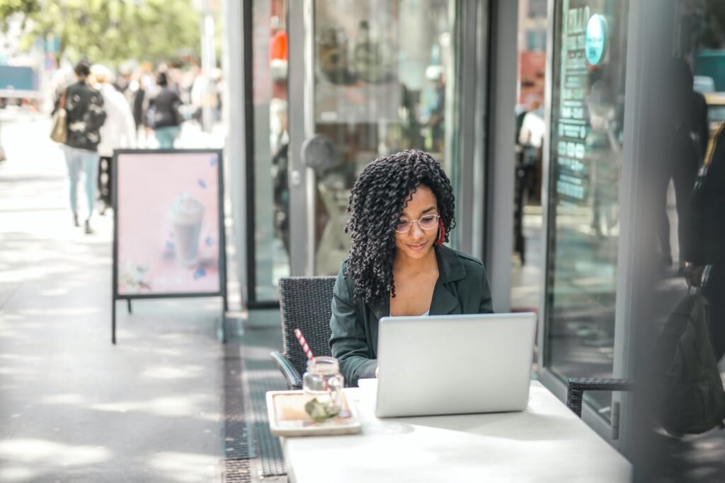 alt="a young woman surfing the laptop computer for affordable education books while sitting on a table outside"