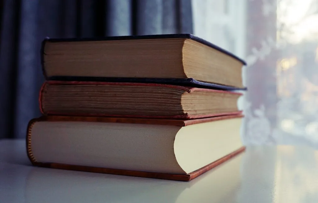 alt="three second hand affordable education books stacked one on top of the the other"