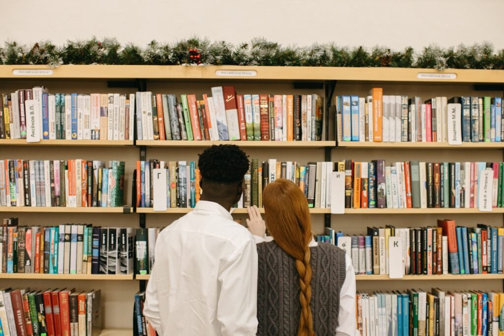 alt="a couple choosing comprehensive education books from bookshelves"