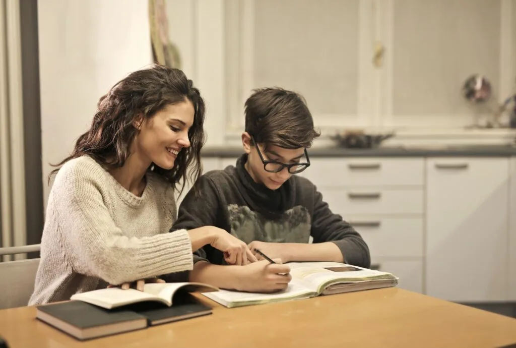 alt="a mother and sun sitting at a table home schooling in an alternative education session"