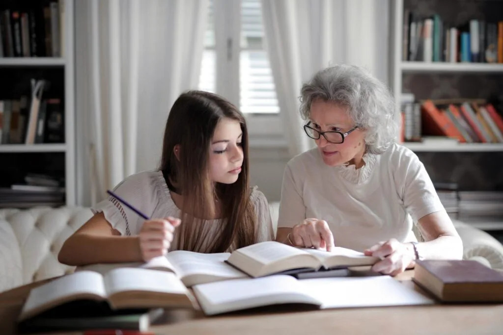 alt="A teacher reviewing open books with a student as part of education dynamics"