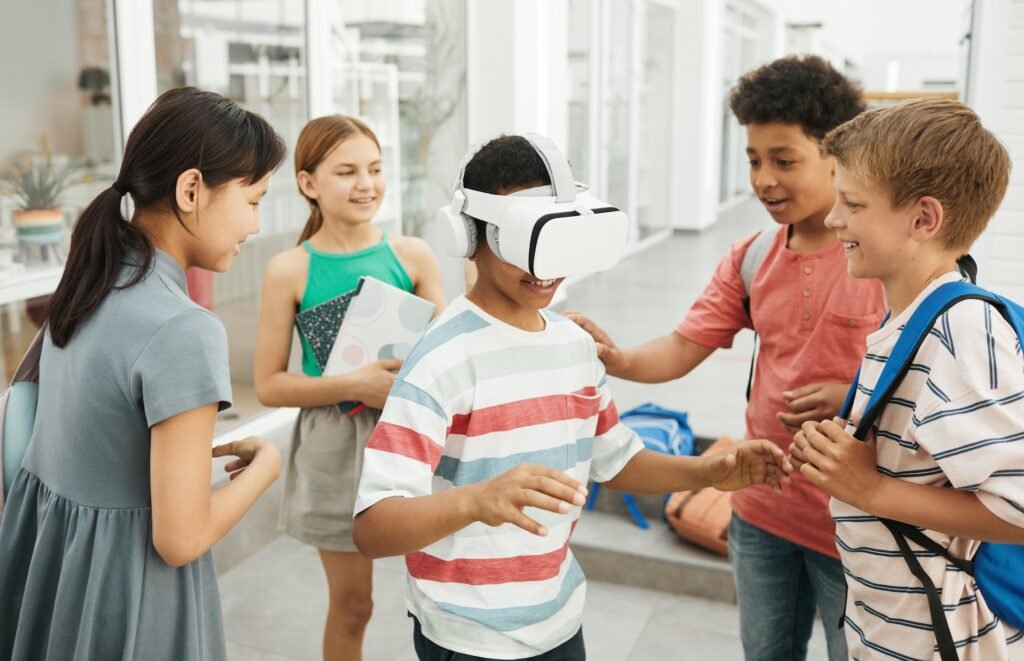 alt="A student wearing a virtual reality glasses surrounded by other students exploring the education dynamics process"