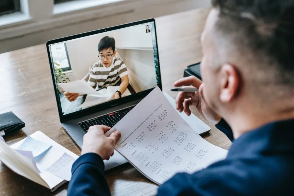 alt="A teacher video zooming with a student reviewing papers as part of education dynamics"