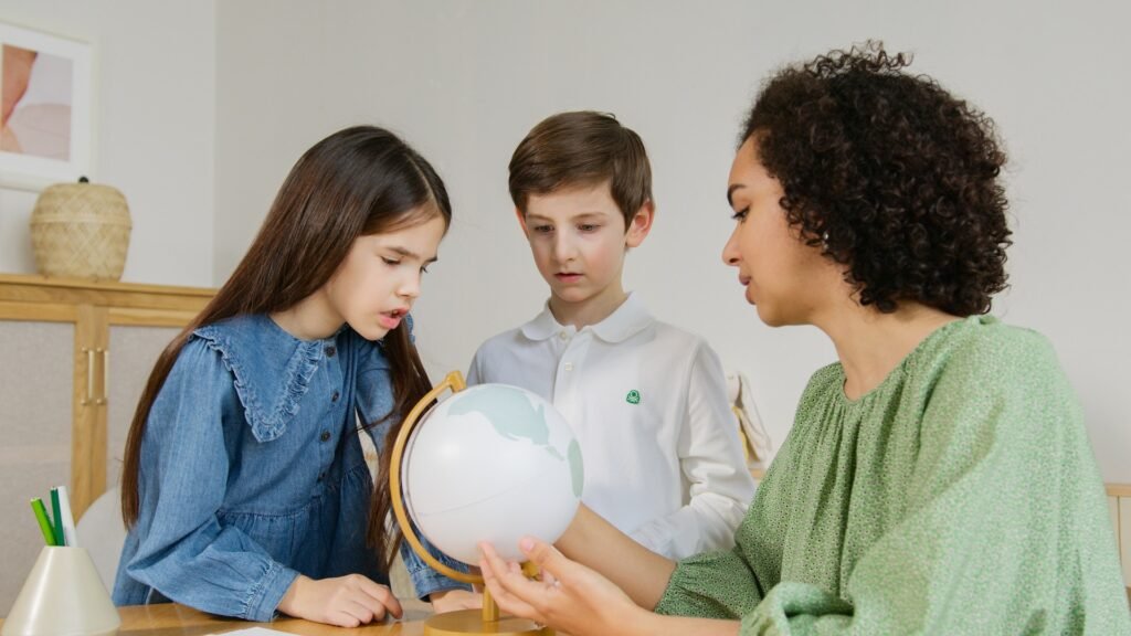 alt="A teacher interacting with two students with a world globe exploring education dynamics process"