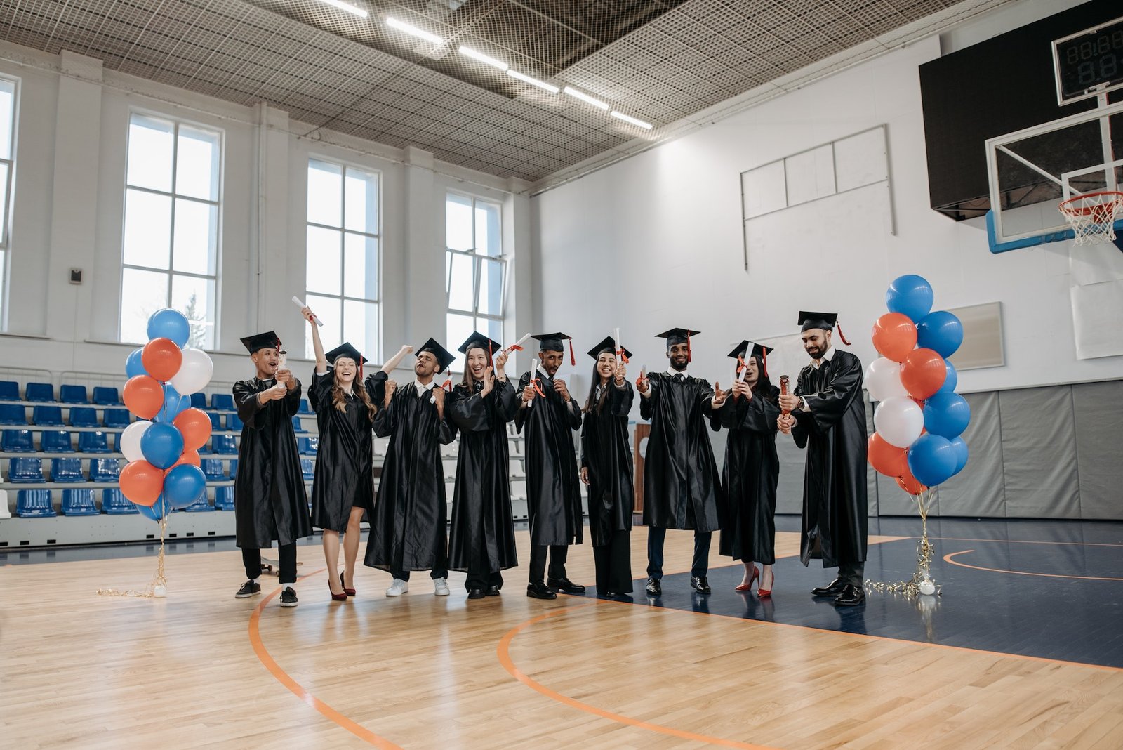 alt="a group of men and women in graduation gown holding up their degrees, part of education background"