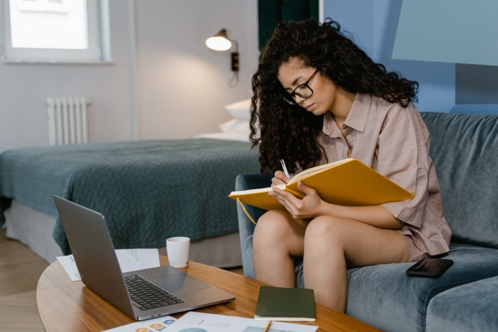alt="A young woman writing on a notebook in from on a computer reviewing education background options"