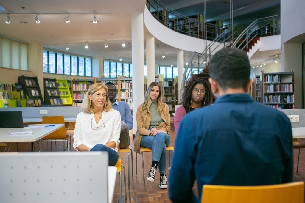 alt="A group of men and women having a meeting at a library part of education icon"