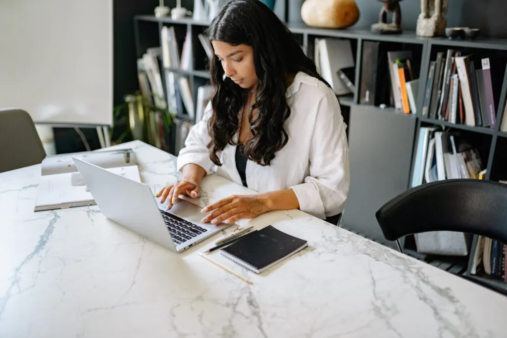 alt="A young woman looking at a laptop working on ideas as part of education icon"
