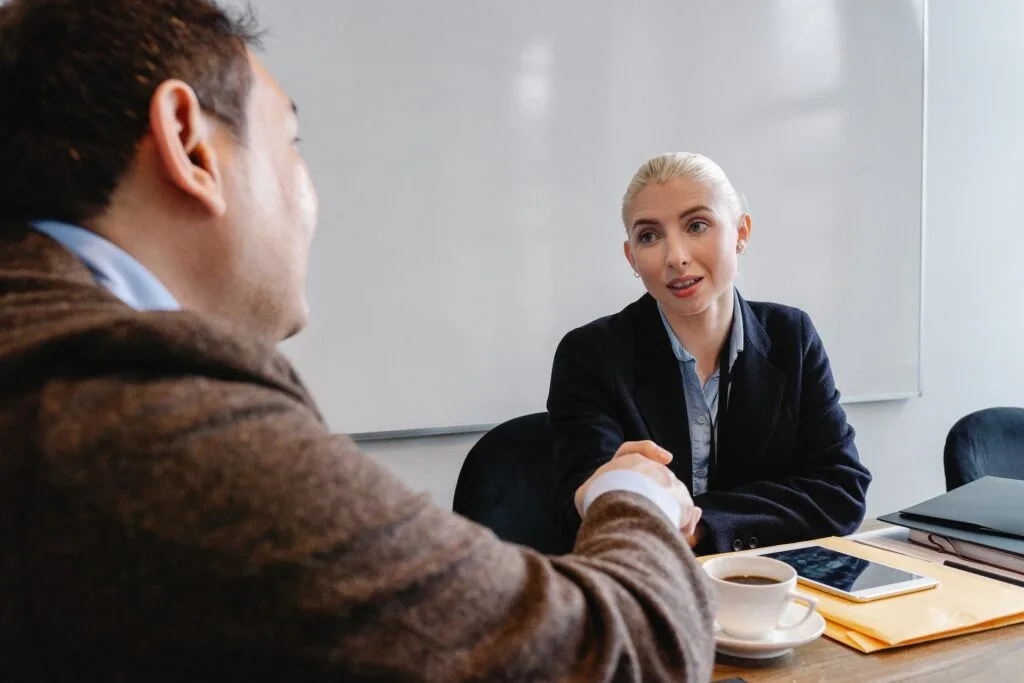 alt="Man and woman shaking hands in an office part of education background"